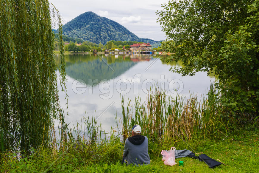 Рыбак с удочкой на берегу горного озера