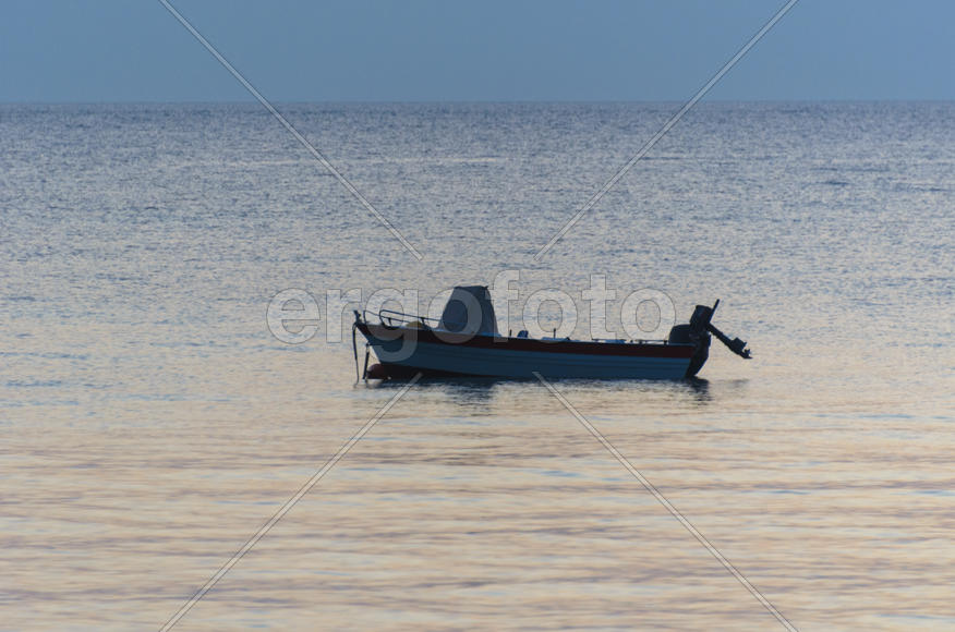 Lonely boat in the sea. Evening sunset.