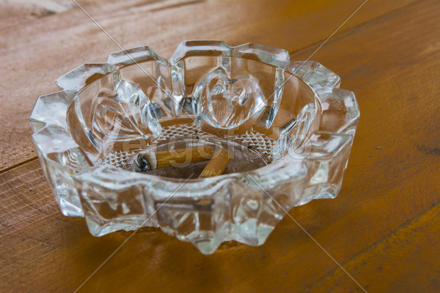 Грязная пепельница с окурками на столе