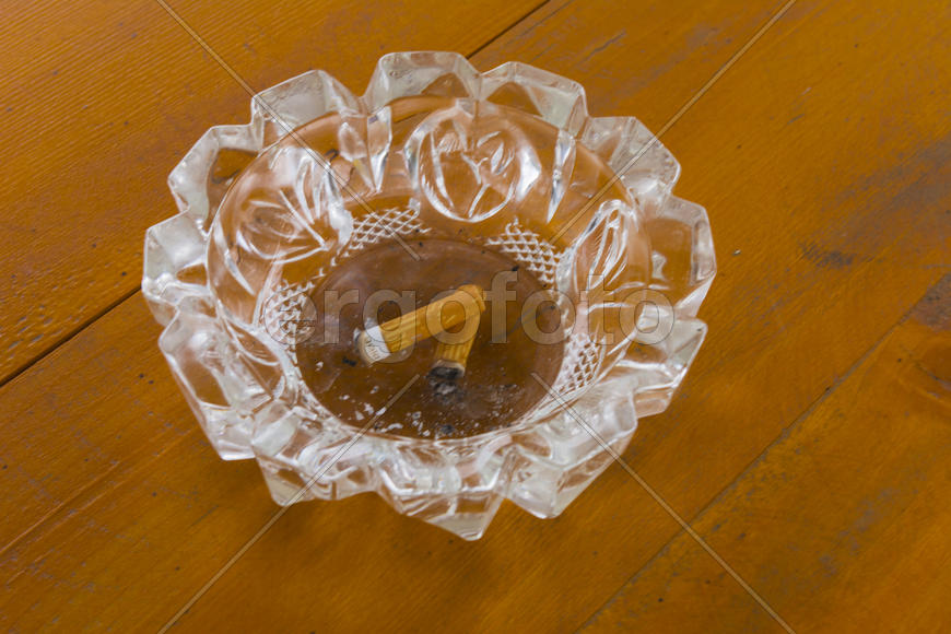 Грязная пепельница с окурками на столе