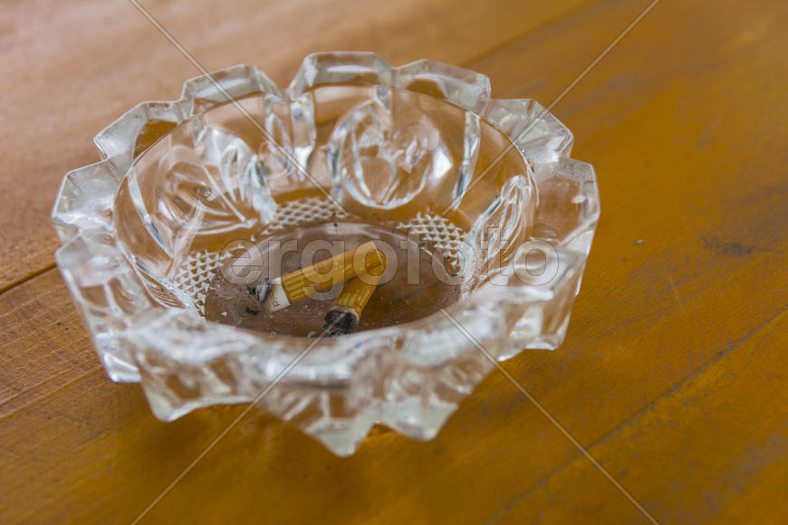 Грязная пепельница с окурками на столе