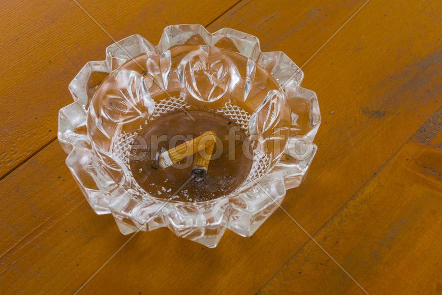 Грязная пепельница с окурками на столе