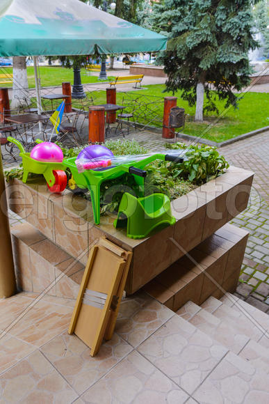 Детские игрушки и горшки на цветочной клумбе 