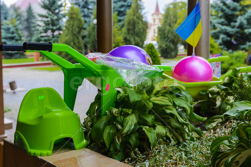 Детские игрушки и горшки на цветочной клумбе 