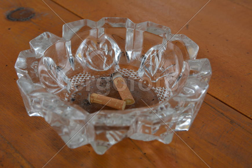 Грязная пепельница с окурками на столе
