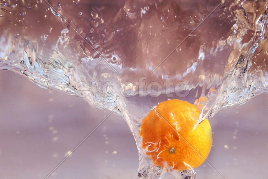 желтый апельсин падает в воду