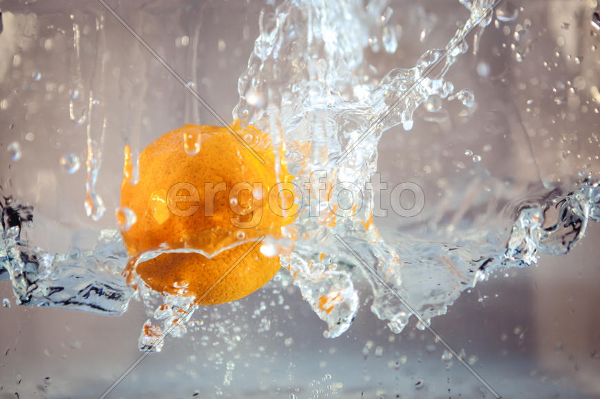 Желтый апельсин падает в воду