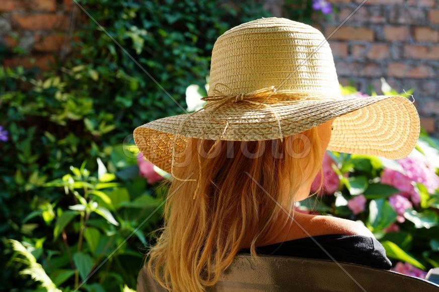 Девушка в шляпе, сидит в саду