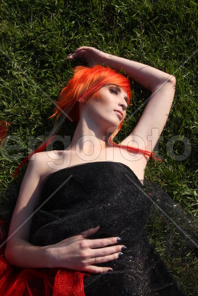 Рыжеволосая девушка в чёрном платье спит на траве