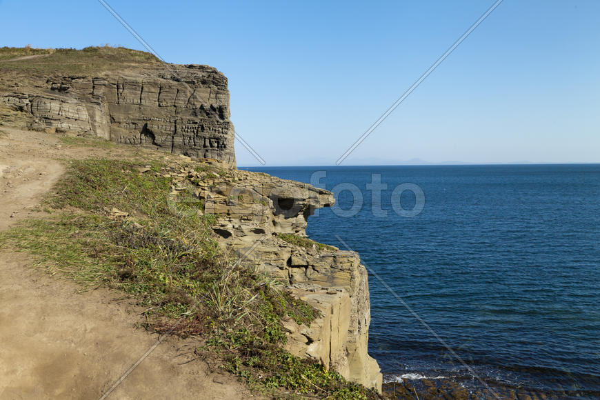Rocks and sea meet in the bright sunlight in autumn