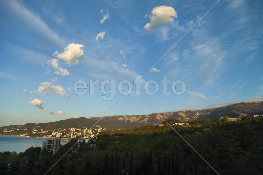 Mountains by the sea at sunrise in beams of the soft sun