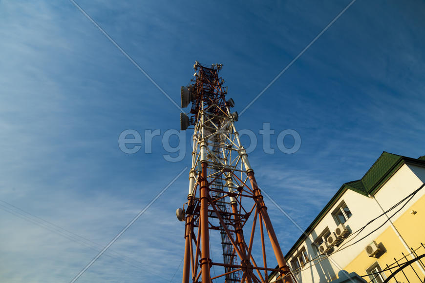 Communication tower against the bright blue sky with clouds
