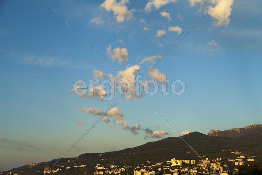 Mountains by the sea at sunrise in beams of the soft sun