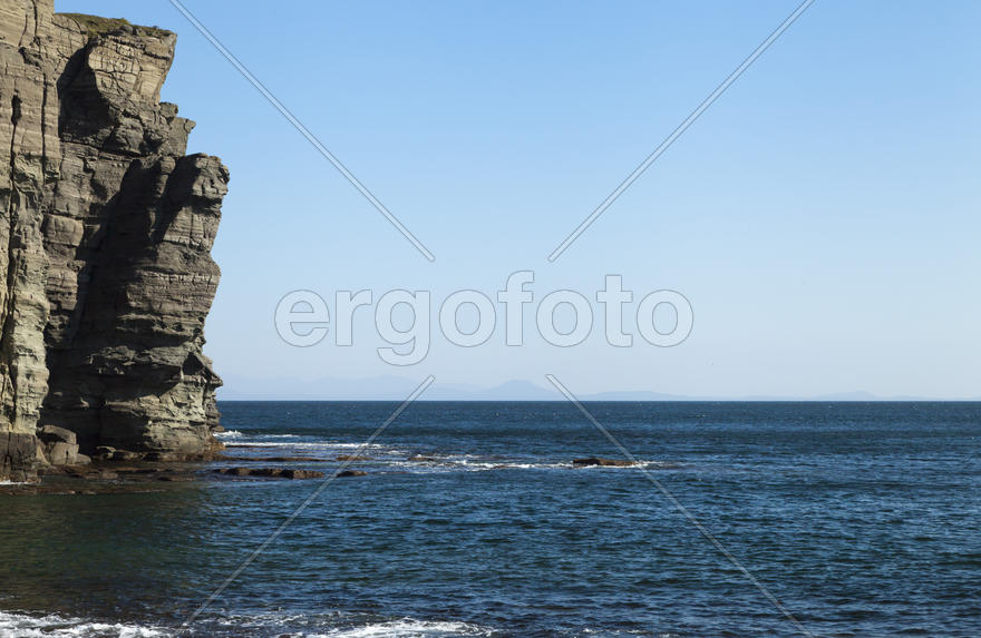 Rocks and sea meet in the bright sunlight in autumn