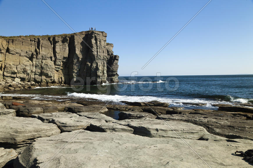Rocks and sea meet in the bright sunlight in autumn