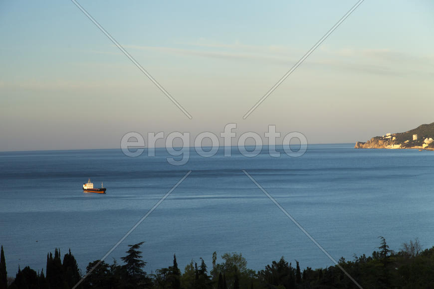 Mountains by the sea at sunrise in beams of the soft sun