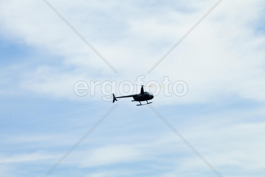 The helicopter in the sky turns over the sea, entertaining people