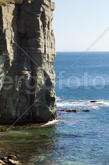 Rocks and sea meet in the bright sunlight in autumn