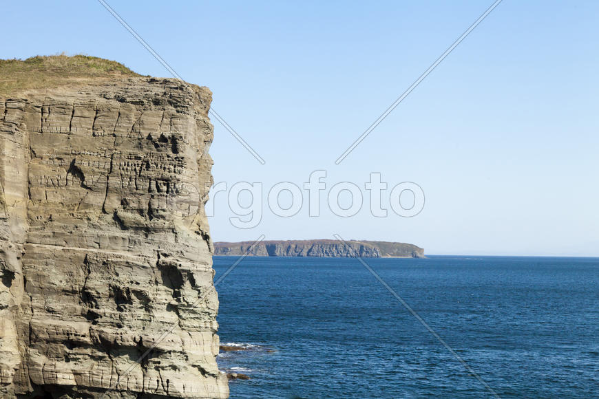 Rocks and sea meet in the bright sunlight in autumn
