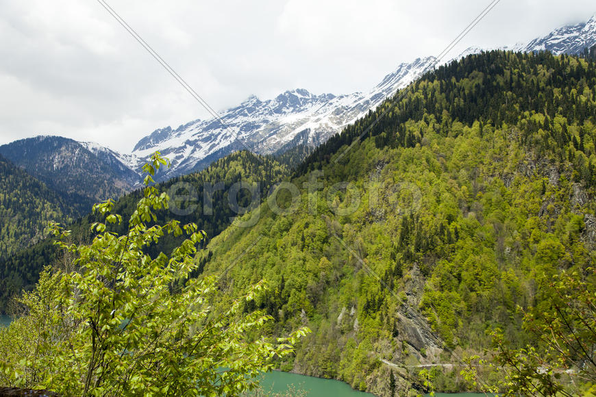 Mountains are covered with snow and the wood and surrounded with clouds