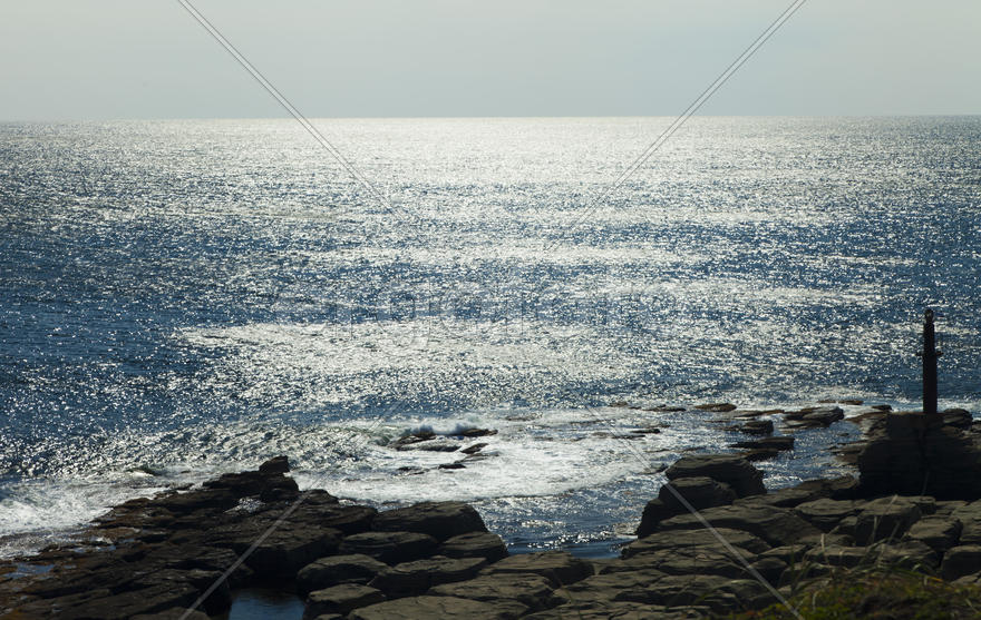 Rocks and sea meet in the bright sunlight in autumn