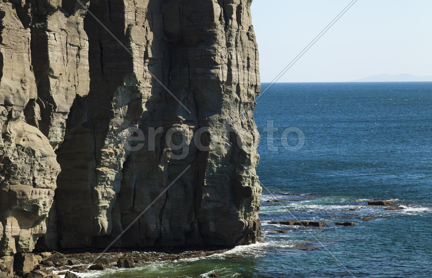Rocks and sea meet in the bright sunlight in autumn