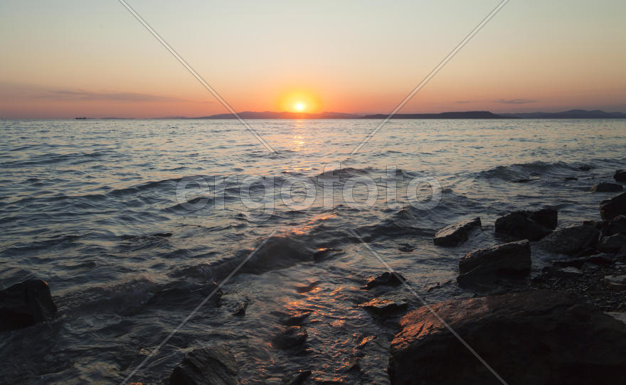 The sea at sunset in beams of the red setting sun