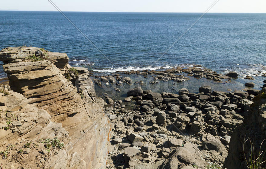 Rocks and sea meet in the bright sunlight in autumn