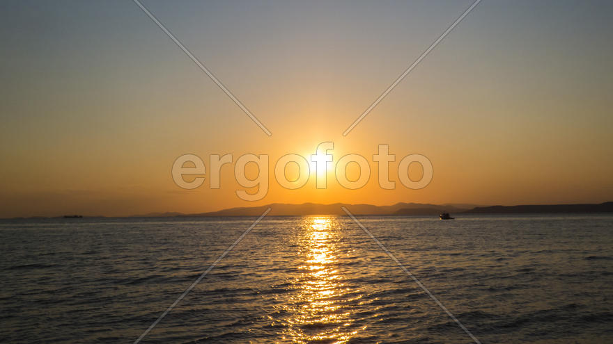 The sea at sunset in beams of the red setting sun