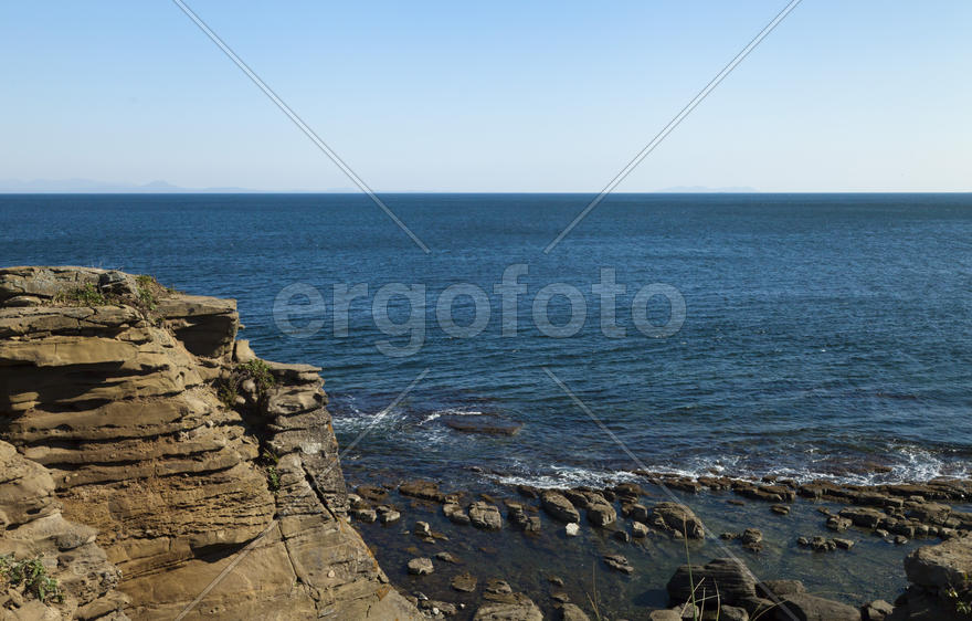 Rocks and sea meet in the bright sunlight in autumn