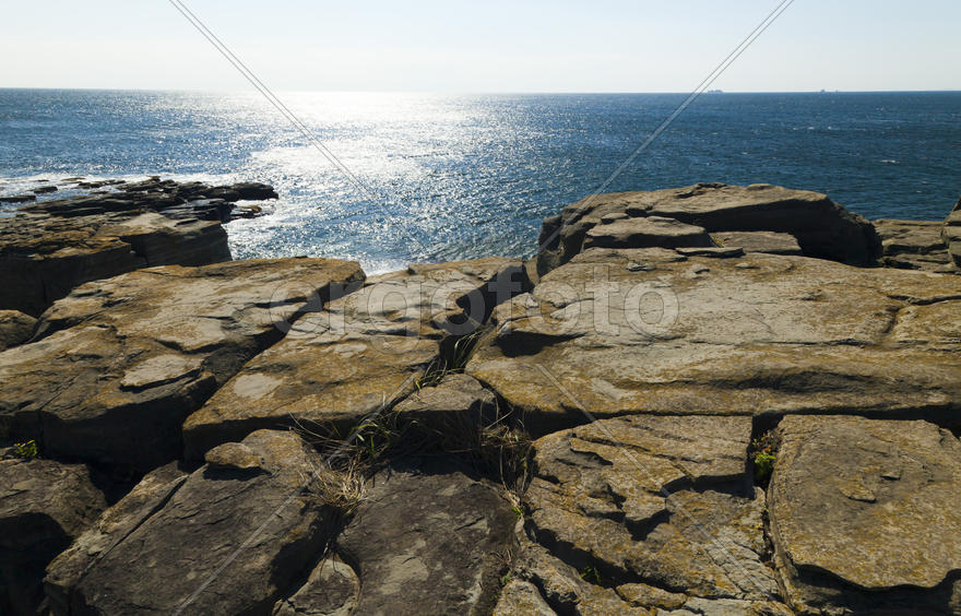 Rocks and sea meet in the bright sunlight in autumn