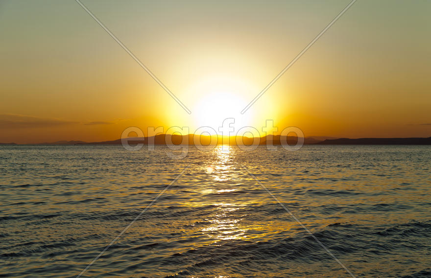 The sea at sunset in beams of the red setting sun