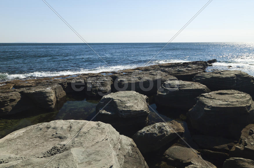 Rocks and sea meet in the bright sunlight in autumn