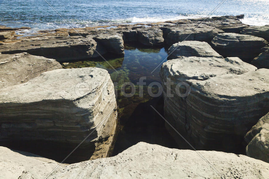 Rocks and sea meet in the bright sunlight in autumn