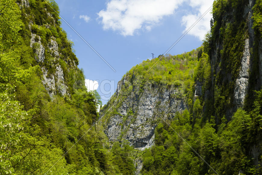 Mountains are covered with snow and the wood and surrounded with clouds