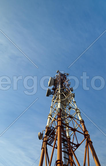 Communication tower against the bright blue sky with clouds