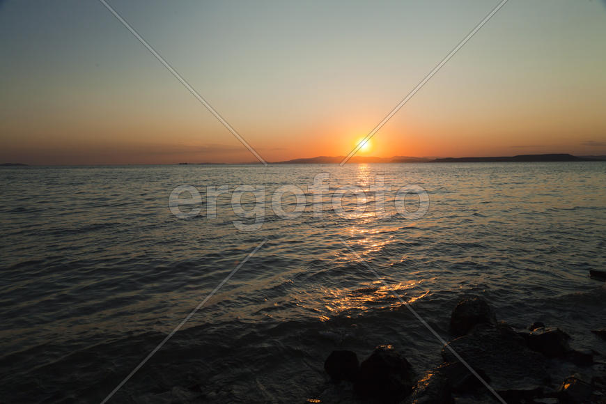 The sea at sunset in beams of the red setting sun