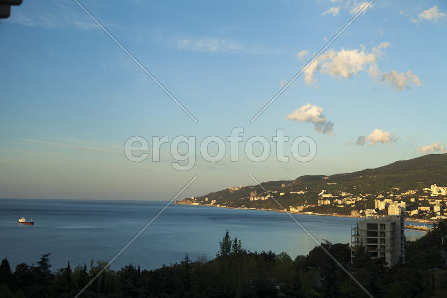 Mountains by the sea at sunrise in beams of the soft sun