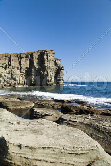 Rocks and sea meet in the bright sunlight in autumn