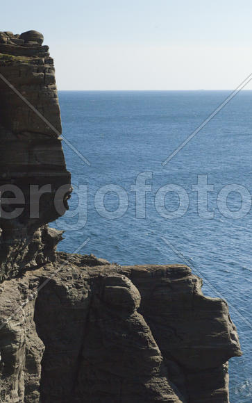 Rocks and sea meet in the bright sunlight in autumn