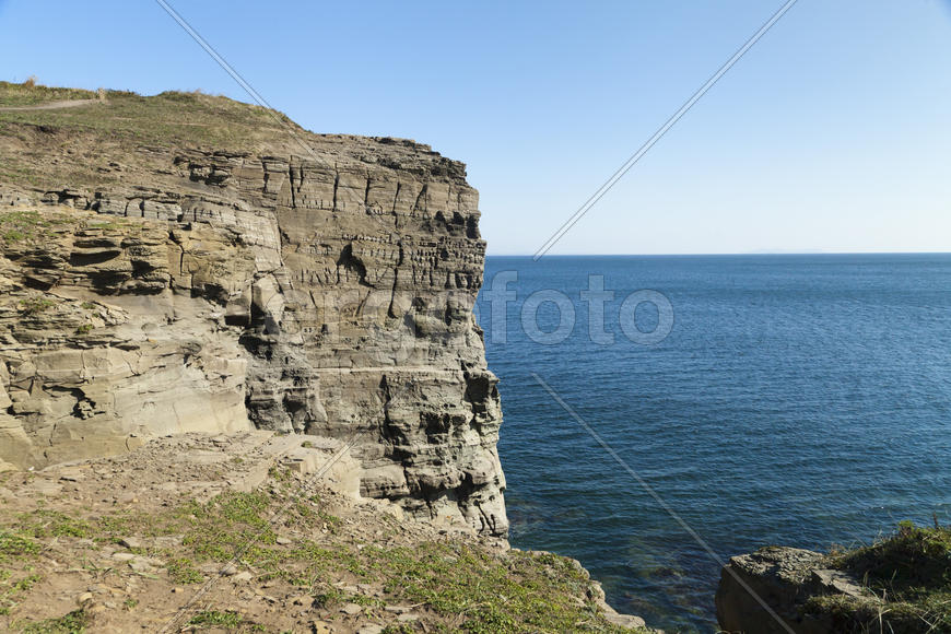 Rocks and sea meet in the bright sunlight in autumn
