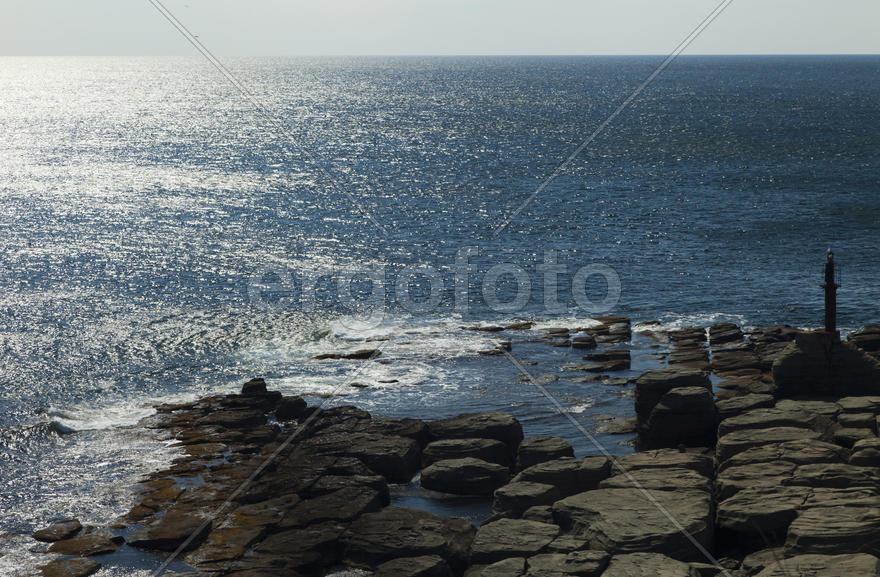 Rocks and sea meet in the bright sunlight in autumn
