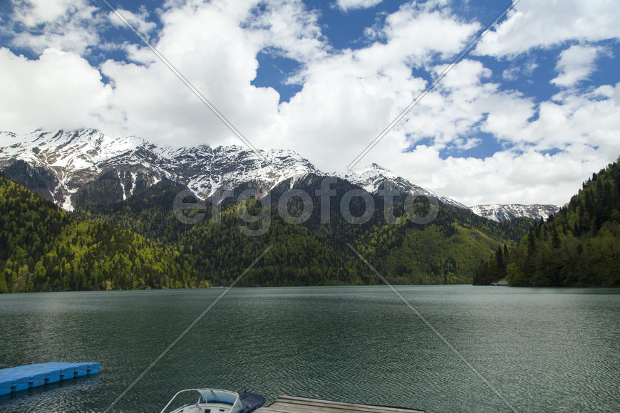 Mountains are covered with snow and the wood and surrounded with clouds