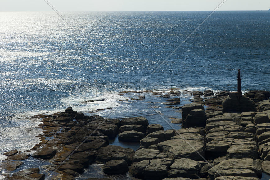 Rocks and sea meet in the bright sunlight in autumn