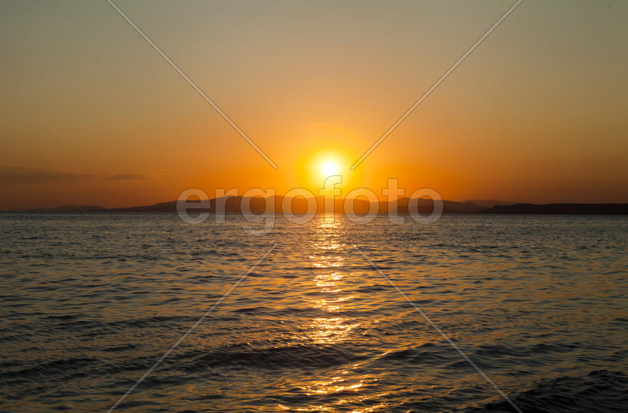 The sea at sunset in beams of the red setting sun