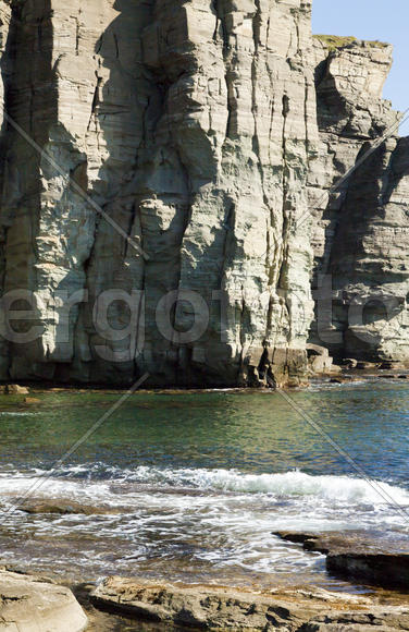 Rocks and sea meet in the bright sunlight in autumn
