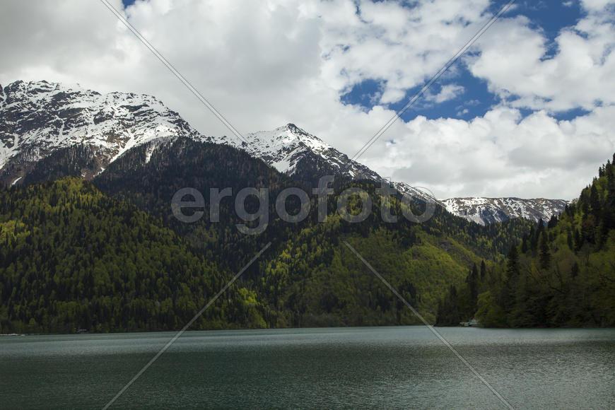 Mountains are covered with snow and the wood and surrounded with clouds