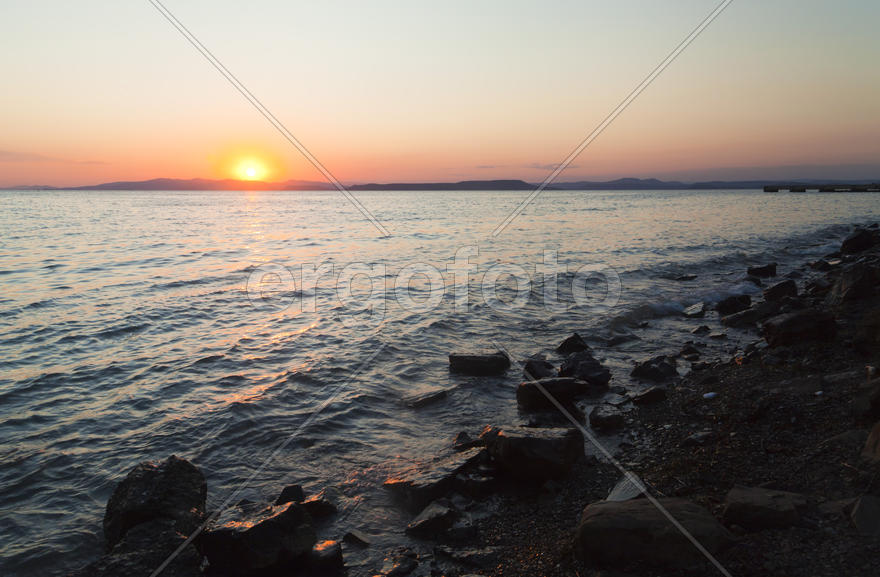 The sea at sunset in beams of the red setting sun