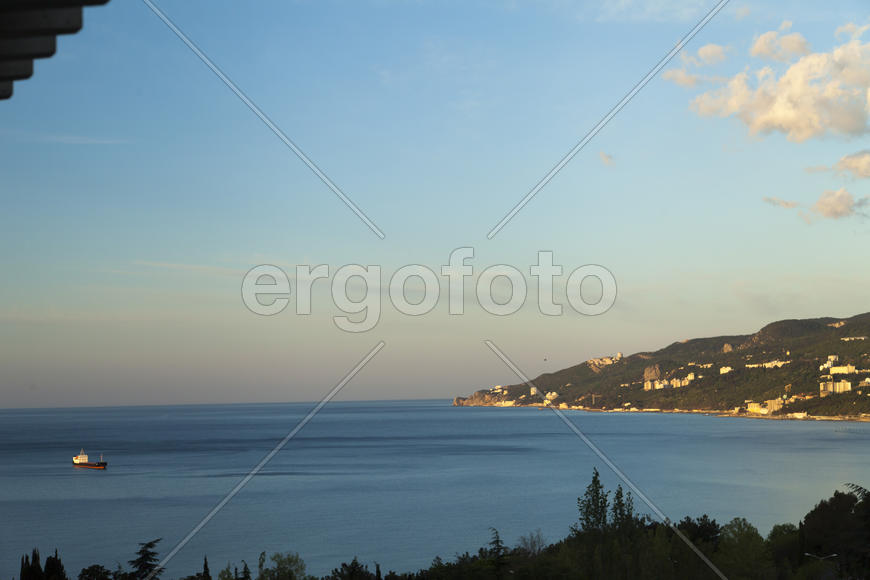 Mountains by the sea at sunrise in beams of the soft sun