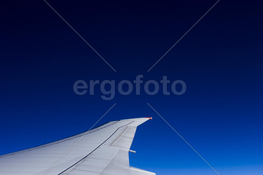 Plane wing against the bright blue sky in flight